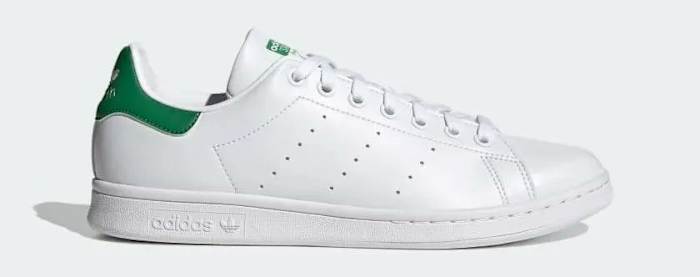 Side view of a white and green adidas shoe.